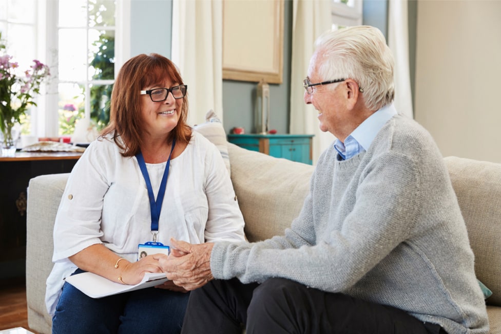 A female nurse consultant is having a conversation with an elderly man