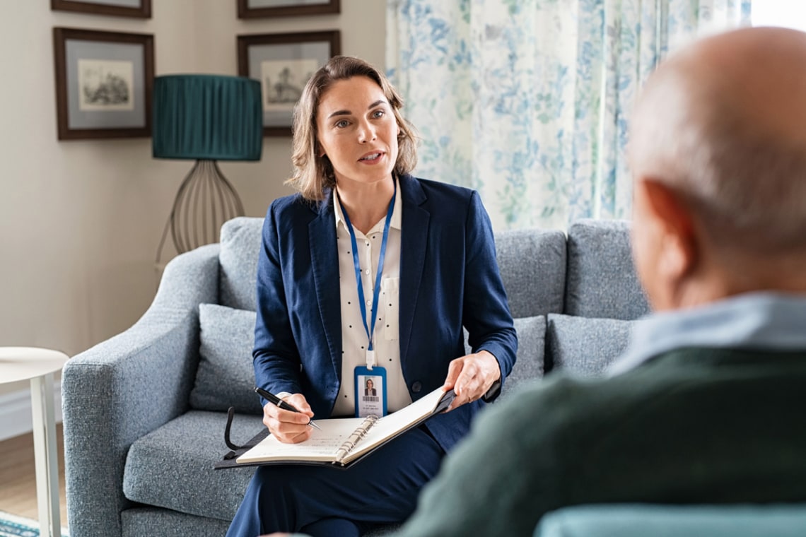 Social worker talking with senior man during home visit