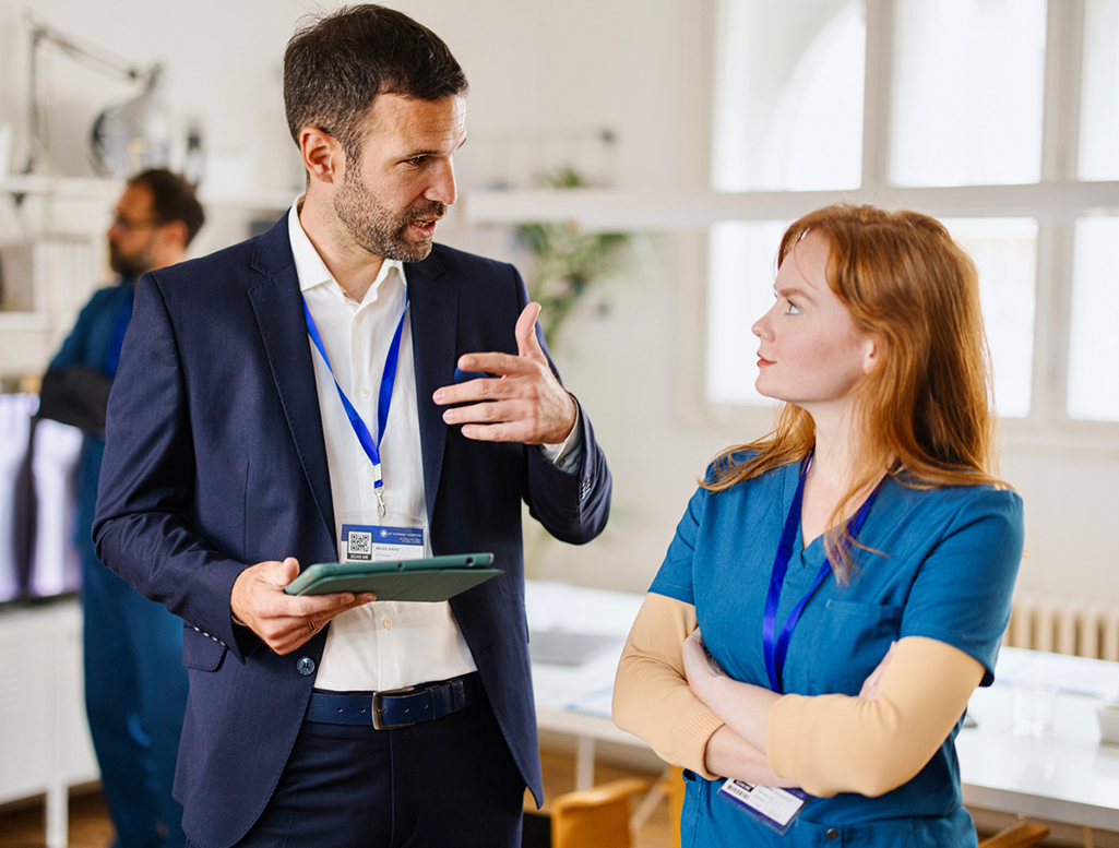 A man in a suit is talking to a female health care worker