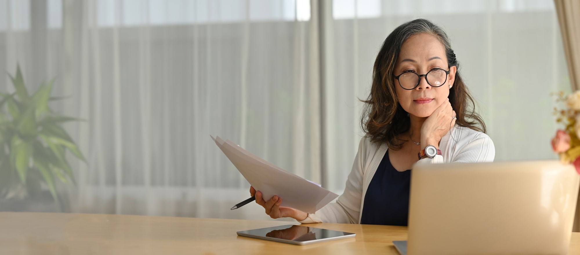 A woman is seated viewing her laptop.