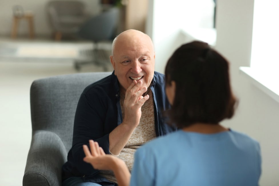 An elderly man is peaking with a health care worker