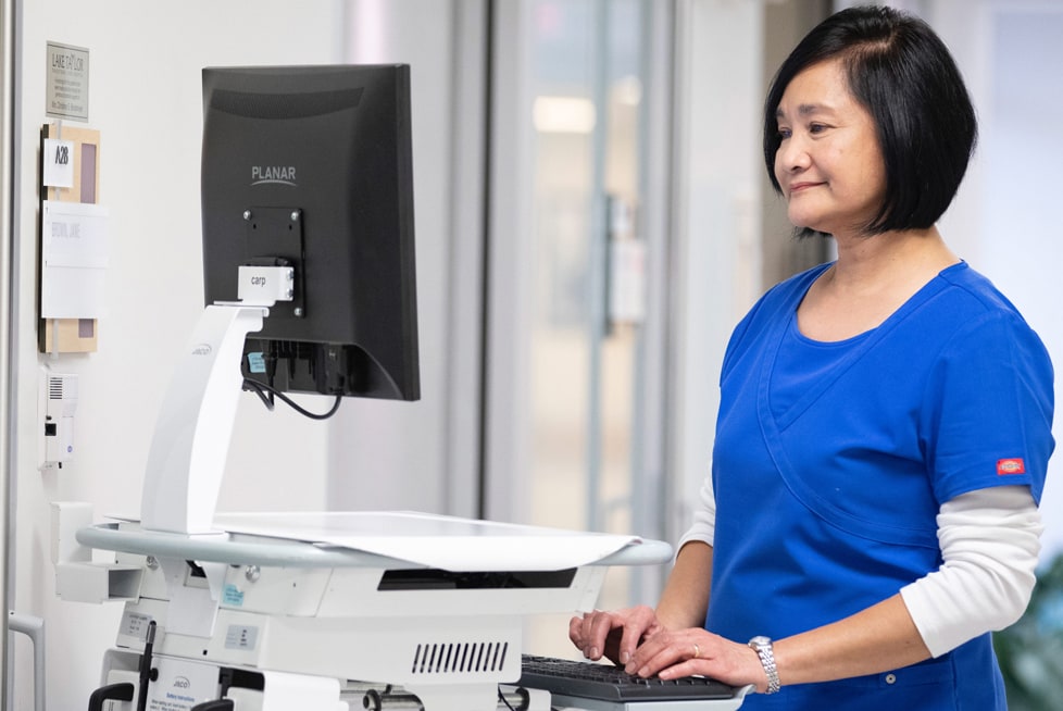 A healthcare worker is typing on a computer keyboard at a work station