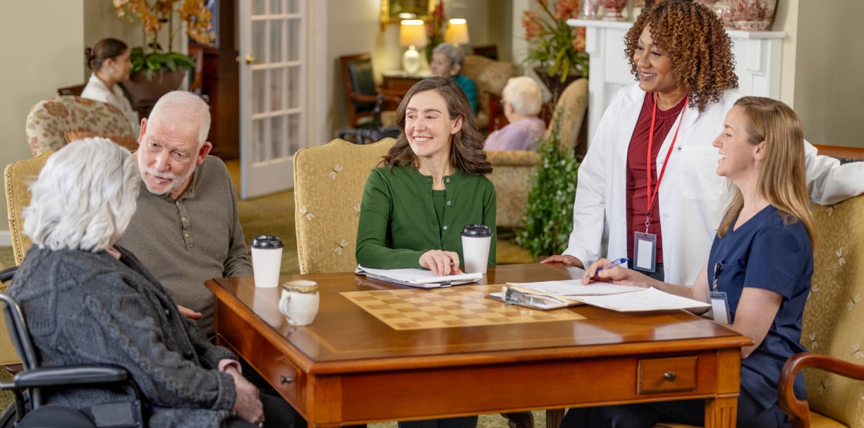 Patients and healthcare workers are socializing around a table.