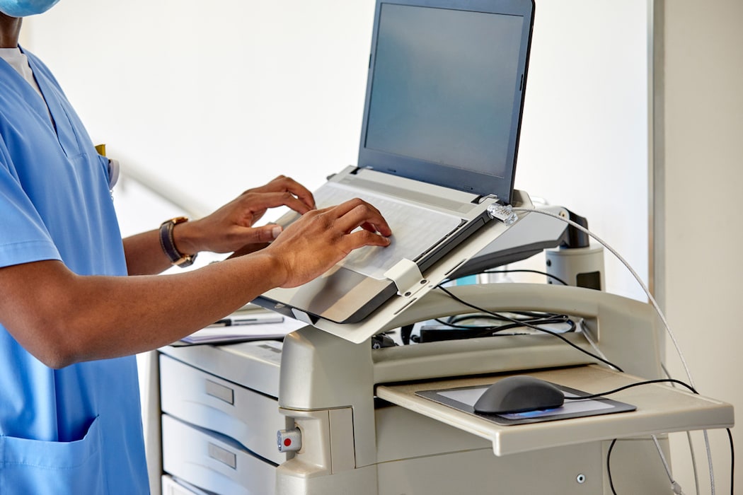 A male healthcare worker is typing on a laptop