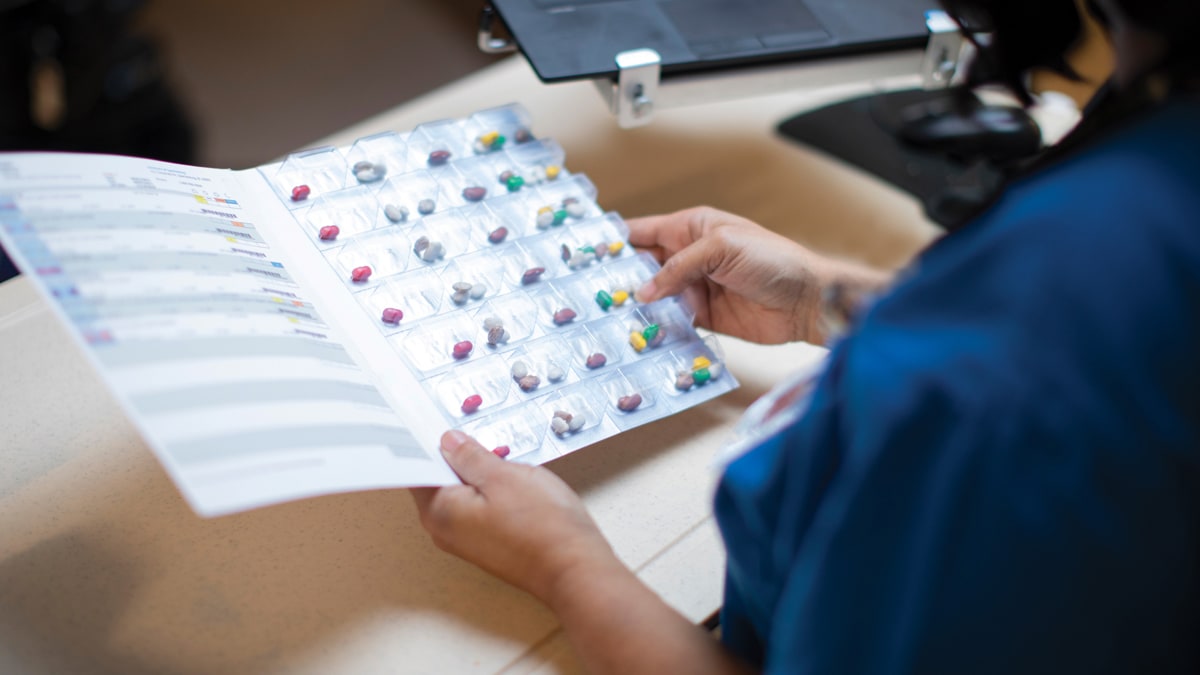 Health care worker checking a patient's medication in a webster pack.