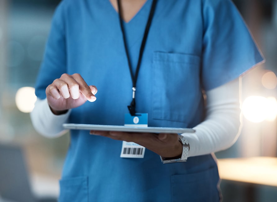 A Healthcare worker's hands are using a tablet device