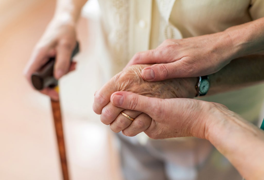 A nurse hands are shown consoling an elderly patients' hands hands