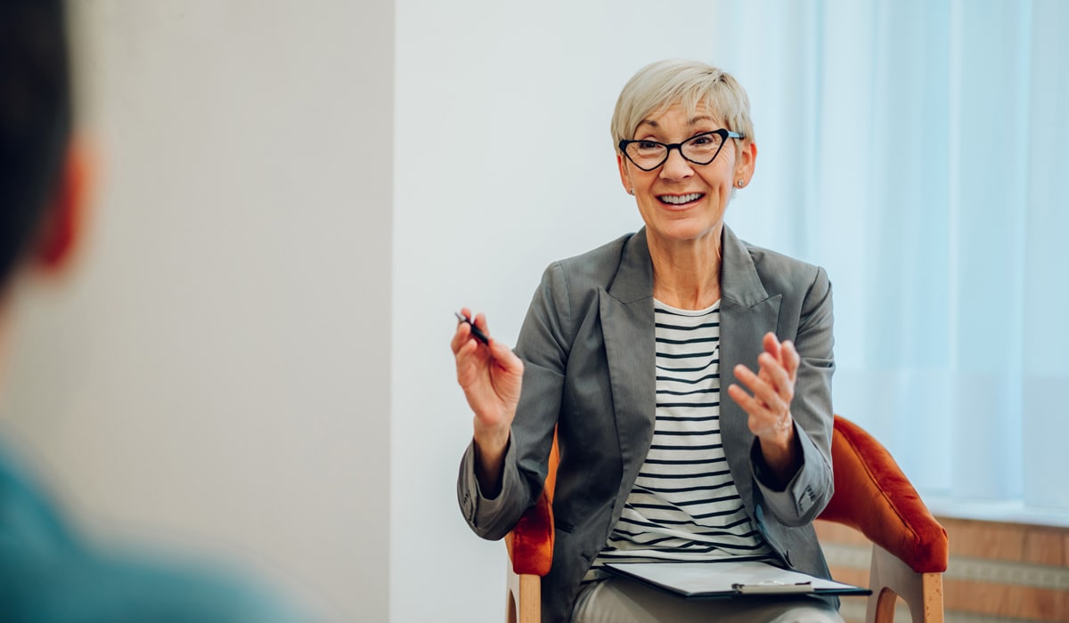 Senior woman psychiatrist talking with her patients during therapy session